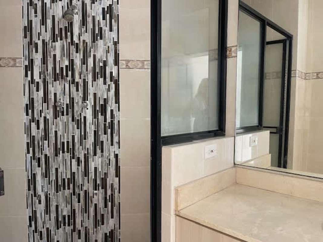 Beige tiled bathroom with glass shower enclosure and vanity in PH Plaza Real Panama