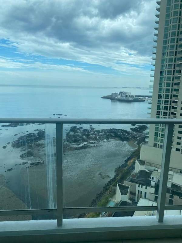 Modern furnished living room with TV wall unit, city skyline view through large window in PH Oceanaire Punta Pacifica