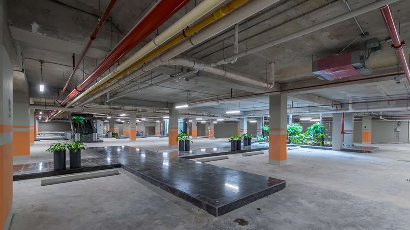 Modern underground parking garage with greenery, exposed concrete, escalator in Panama Design Center Costa del Este