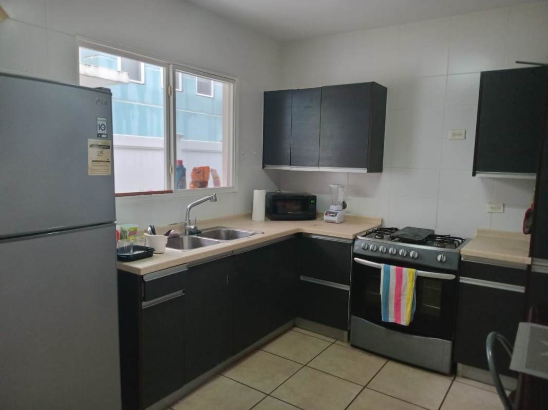 Kitchen area with cabinets, stove, microwave in PH Alpes townhouse Panama City