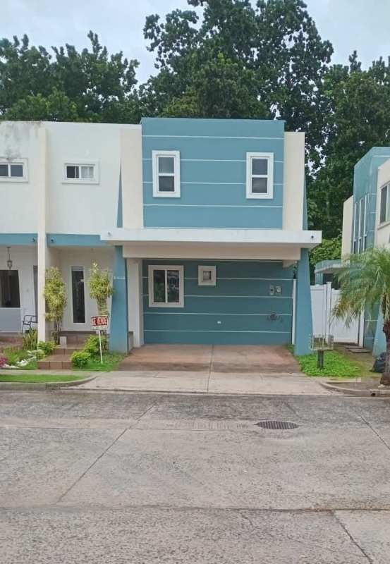 Blue and white two-story townhouse facade, covered carport, PH Alpes Brisas Norte