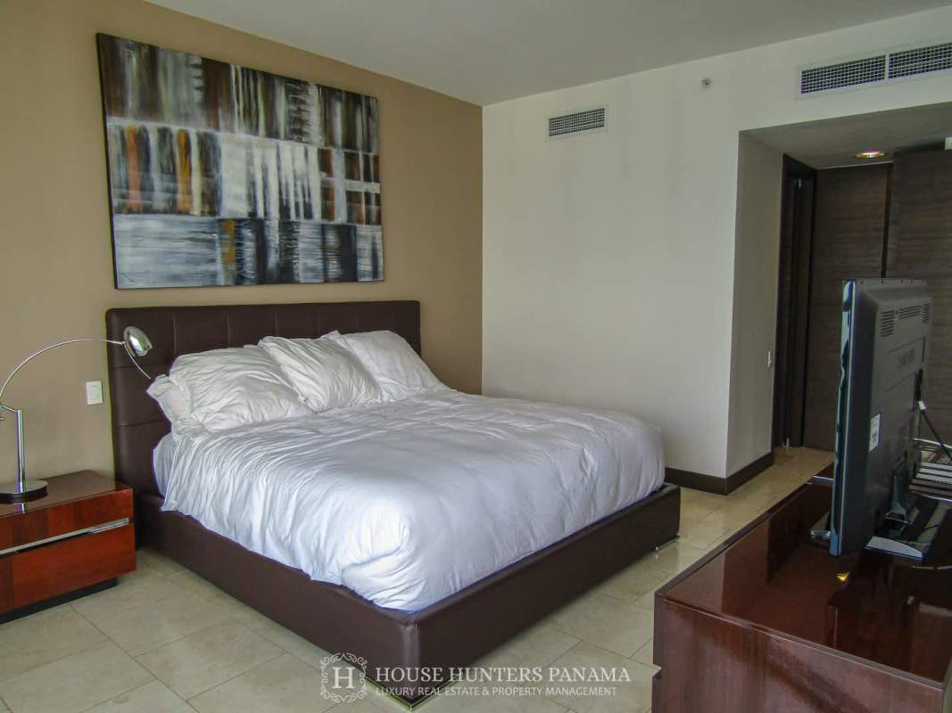 Stylish bedroom with large bed, TV, marble floors and modern furnishings in The Ocean Club Panama City