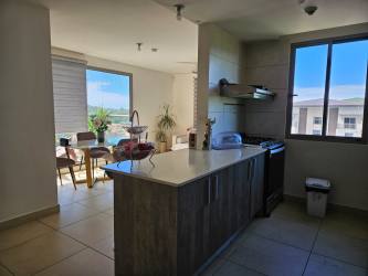 Modern kitchen island with dining area, large windows and natural light in Panama Pacifico apartment