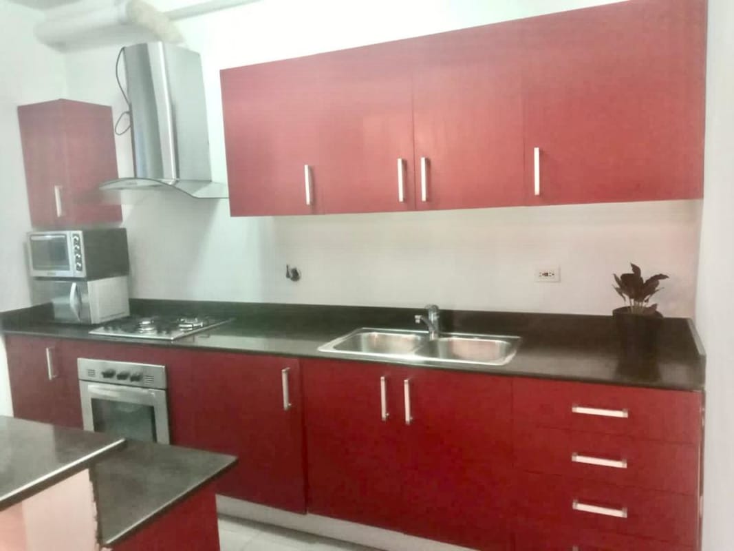 Stylish kitchen with red cabinets, granite counters, stainless appliances in PH Quartier 74 near Parque Omar Panama City