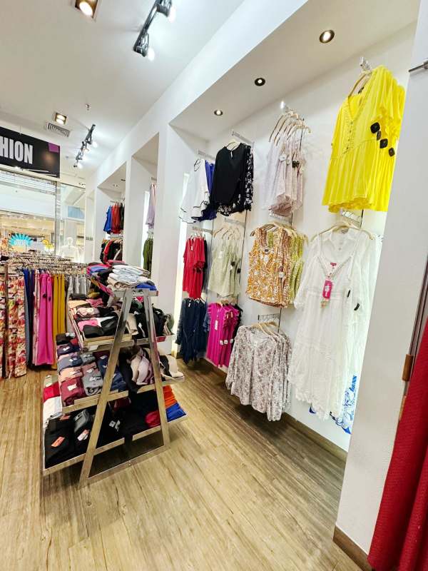 Bright retail clothing boutique in Metromall Panama with racks and colorful accent wall