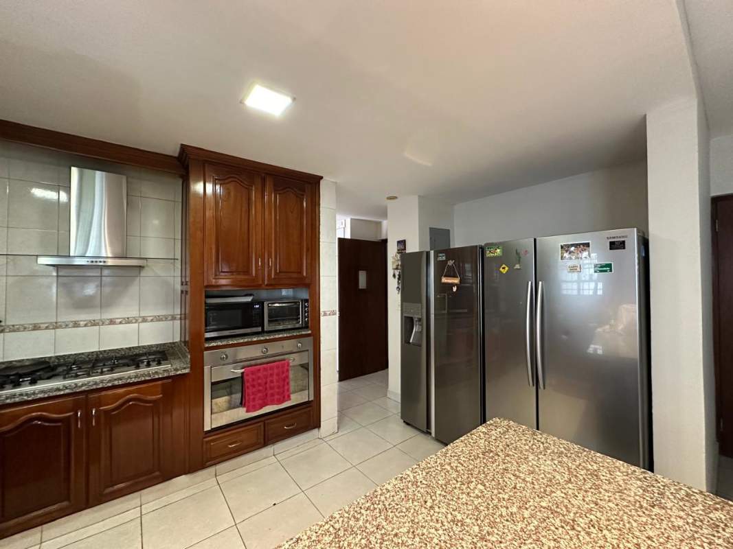 Kitchen with granite counters, wood cabinets, double door fridge in house La Alameda Panama