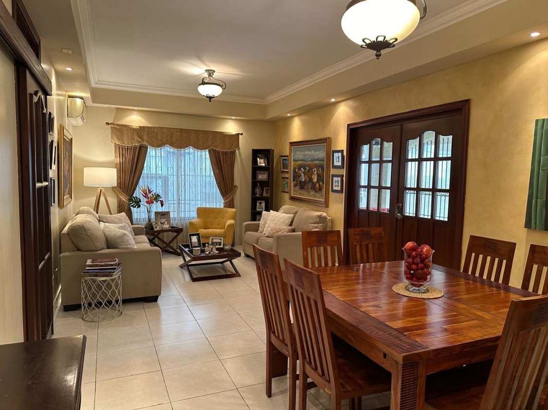 Traditional dining room with wood furniture open to living space in La Alameda house Panama City