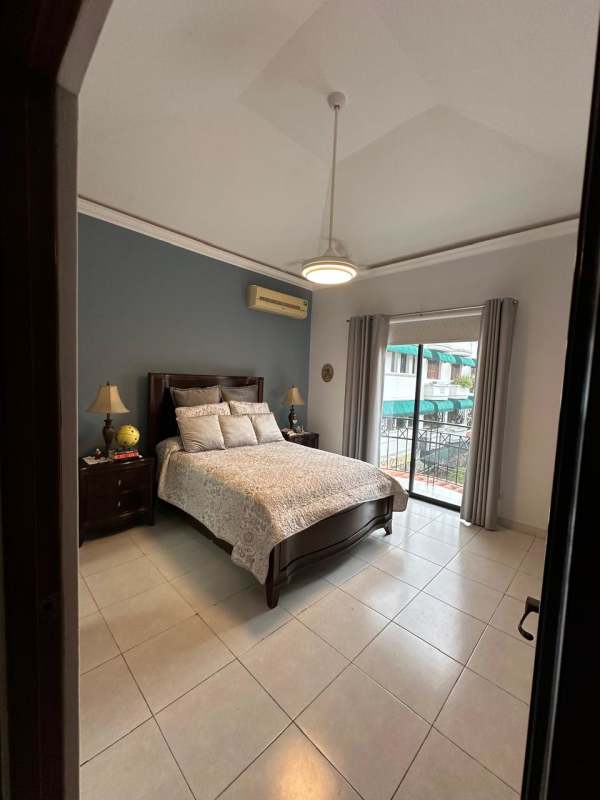Bedroom with large sliding doors to balcony, wood floors in La Alameda residence Panama City
