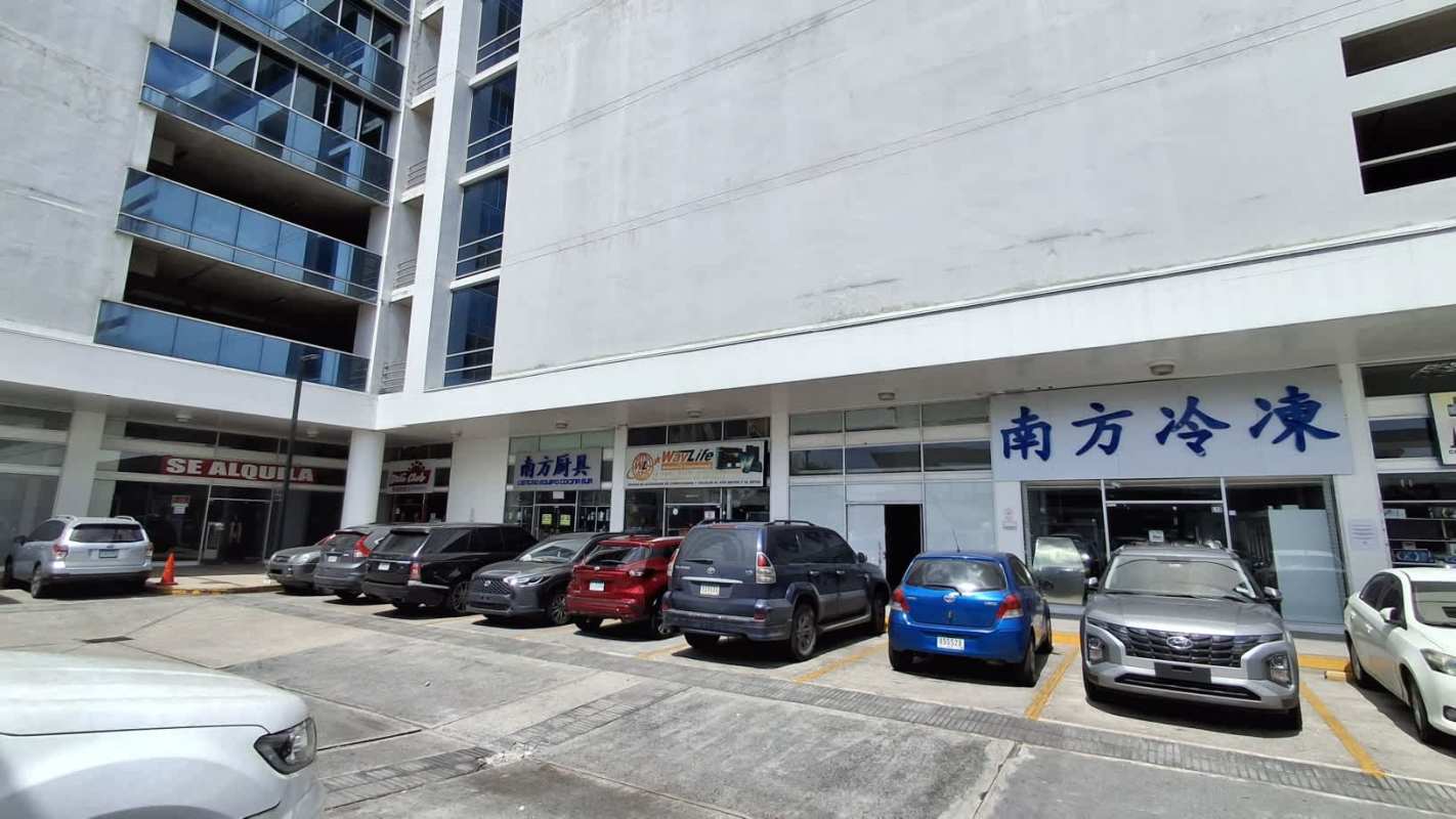 Multi-level commercial plaza with parked cars, retail units, and signage in Condado del Rey Panama City