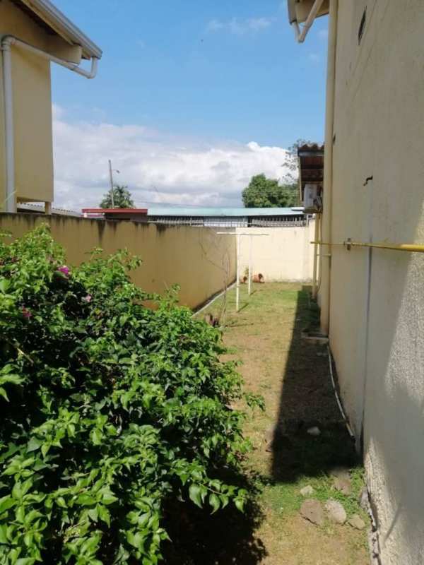 Fenced backyard with garden plants, privacy wall, clothesline beside yellow house in Cerro Viento Panama City