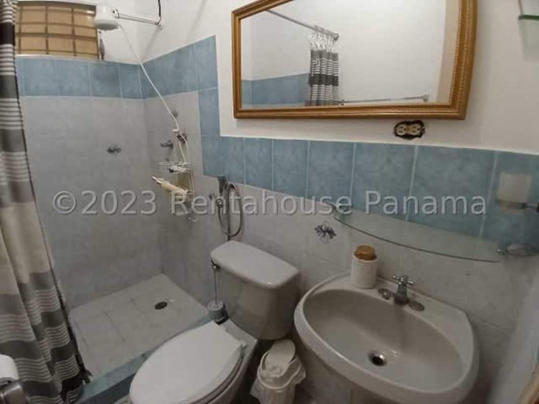 Bathroom with blue-white tiles, shower, and classic mirror at remodeled house Villa Lucre Panama City