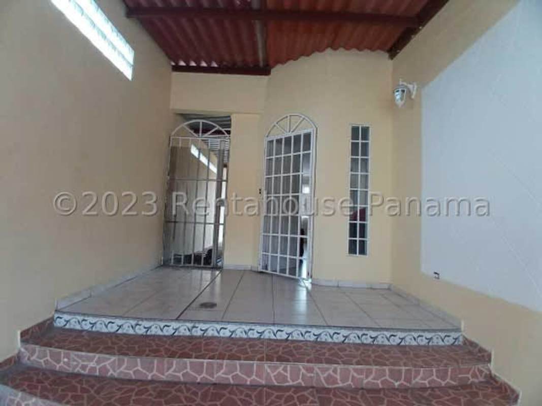 Covered porch entry with metal security gate and glass doors in Villa Lucre El Crisol house