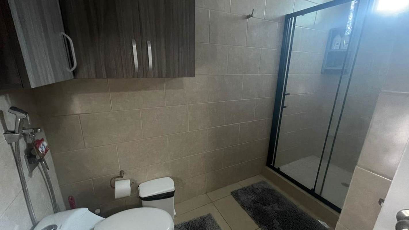 Contemporary bathroom with glass shower, beige tiles, modern fixtures at PH Red Point, Panama City