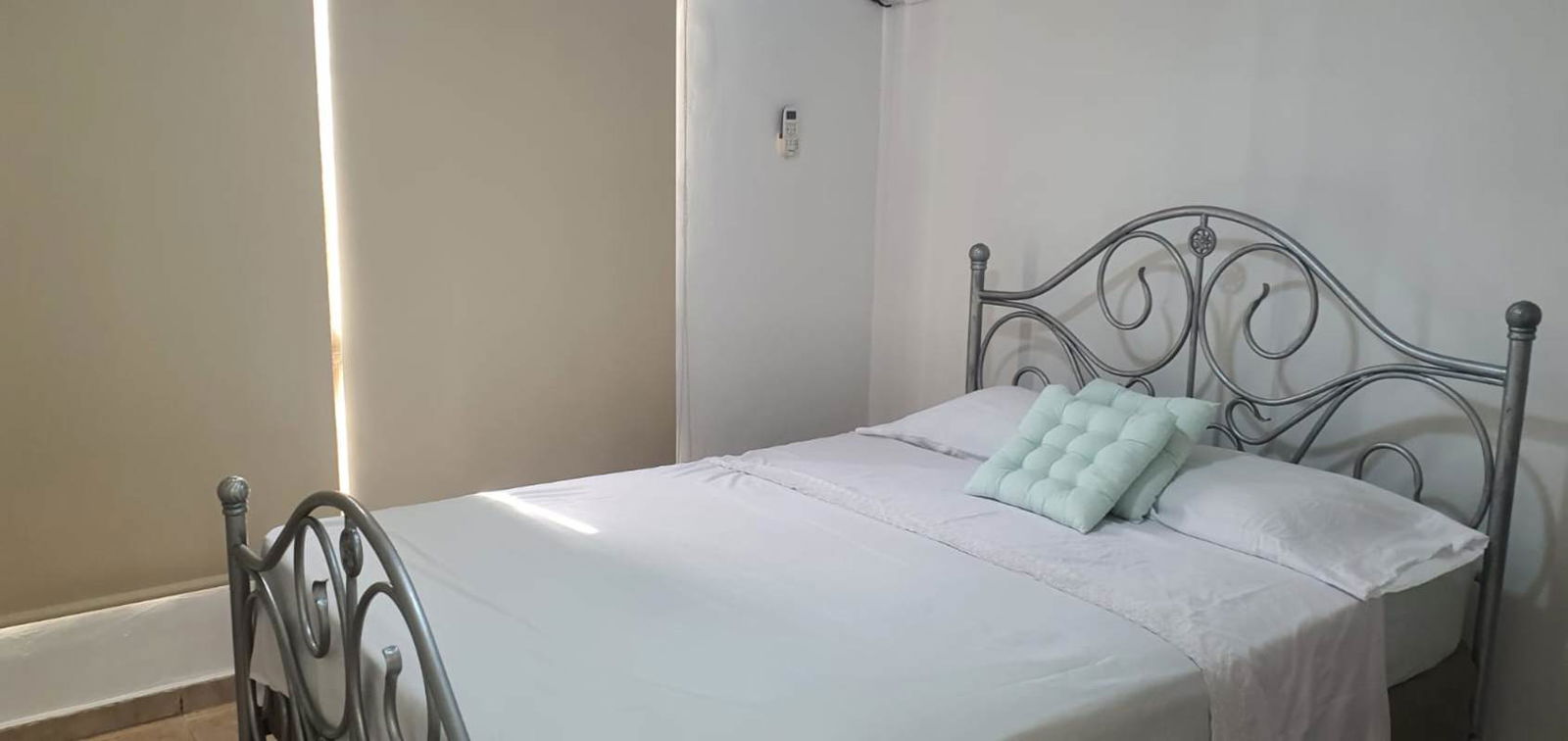 Minimalist bedroom with air conditioning, metal bed frame and white bedding PH Edison Park Panama City