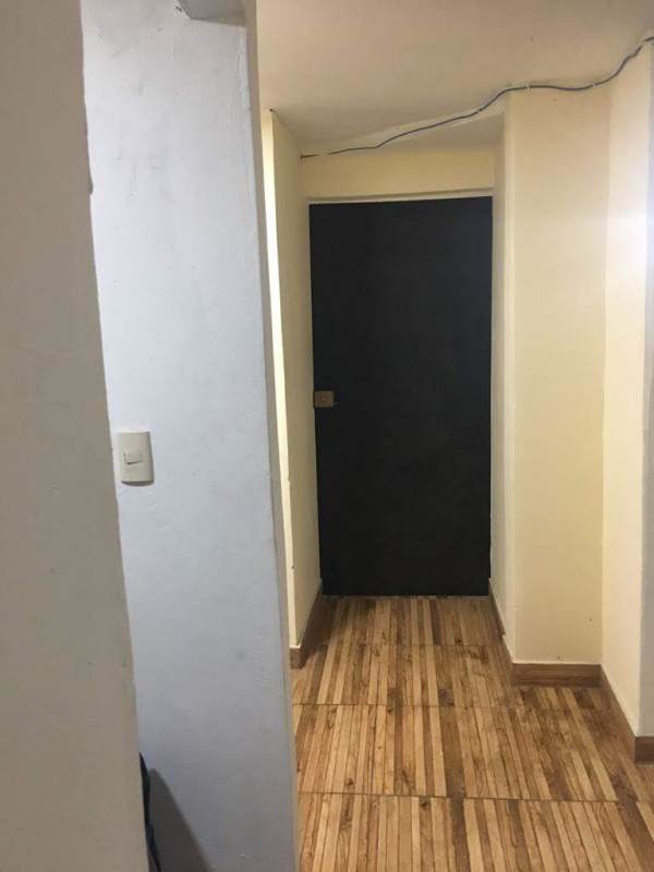 Narrow hallway with beige walls, laminate floor, black door Carrasquilla Plaza Panama