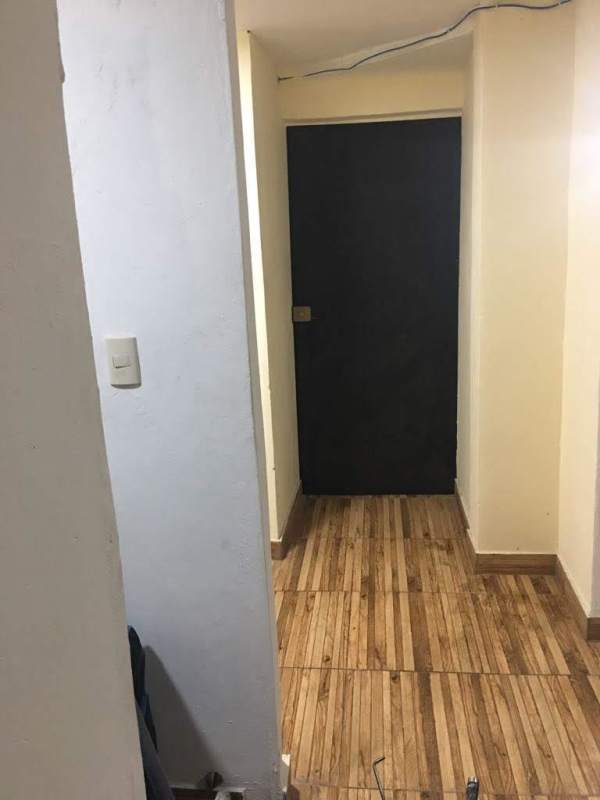 Interior hallway with wooden tiles and black door PH Carrasquilla Plaza Panama