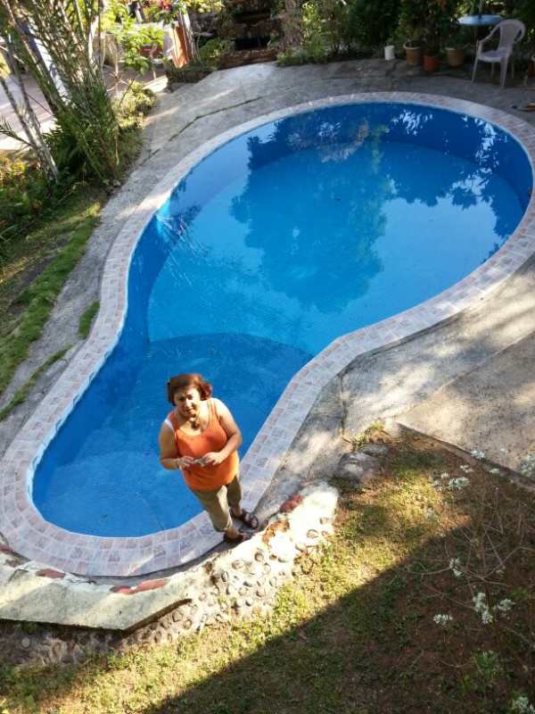 Aerial view of kidney-shaped private pool with deck surrounded by garden landscaping and mountain backdrop in Cerro Azul Panama