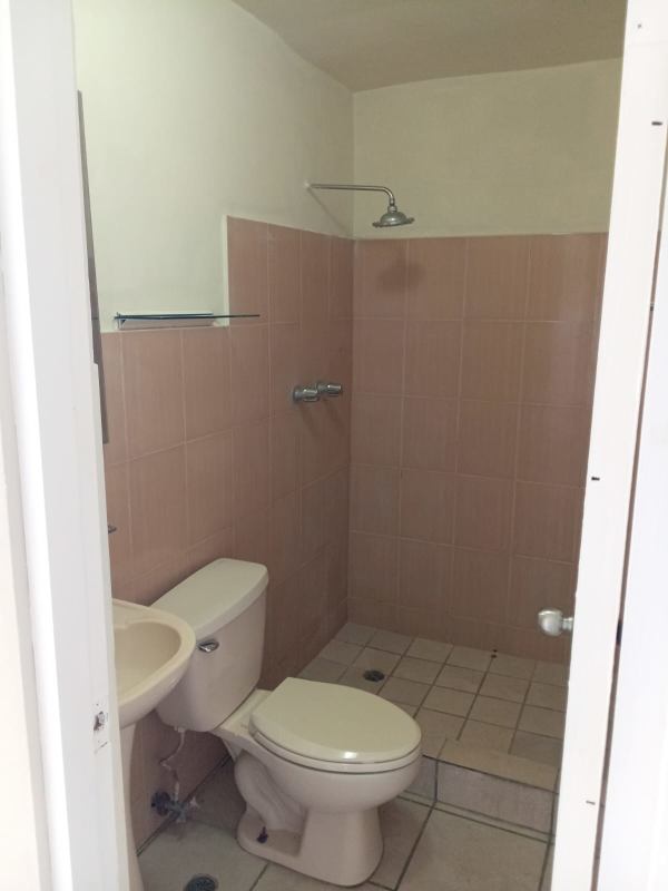Small bathroom with beige tile shower, toilet and pedestal sink in PH Las Lomas Hato Pintado Panama apartment