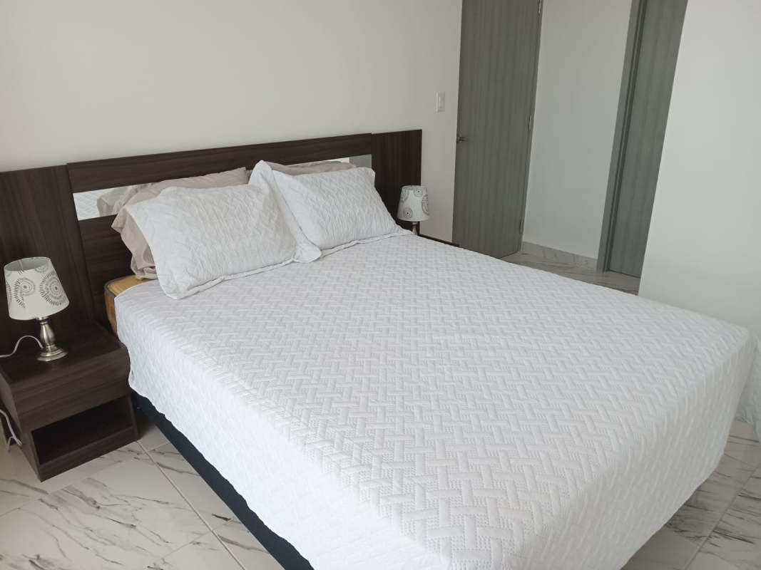 Bedroom with white bedspread, dark wood headboard, marble floor apartment at PH BICSA Panama