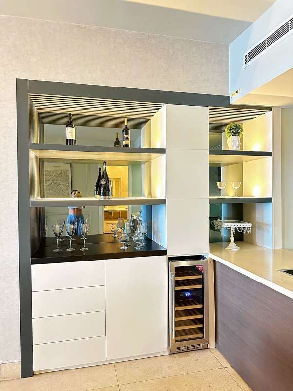 Home bar with built-in wine cooler, shelving and accent lighting inside Yoo Panama apartment