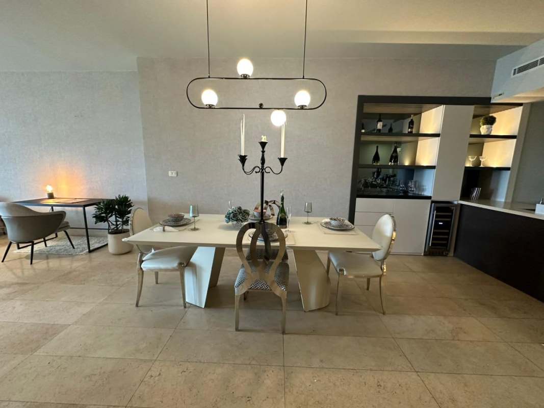 Elegant dining area with glass table, pendant lighting, bar shelves and workspace Yoo Panama