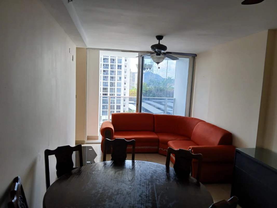 Living dining space with orange sectional sofa, dining table, balcony access in Condado Country Club Condado del Rey Panama