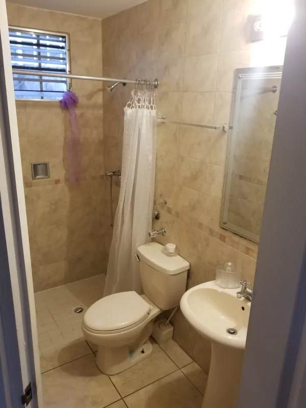 Modern tiled bathroom with walk-in shower and pedestal sink in Brisas del Golf Panama rental