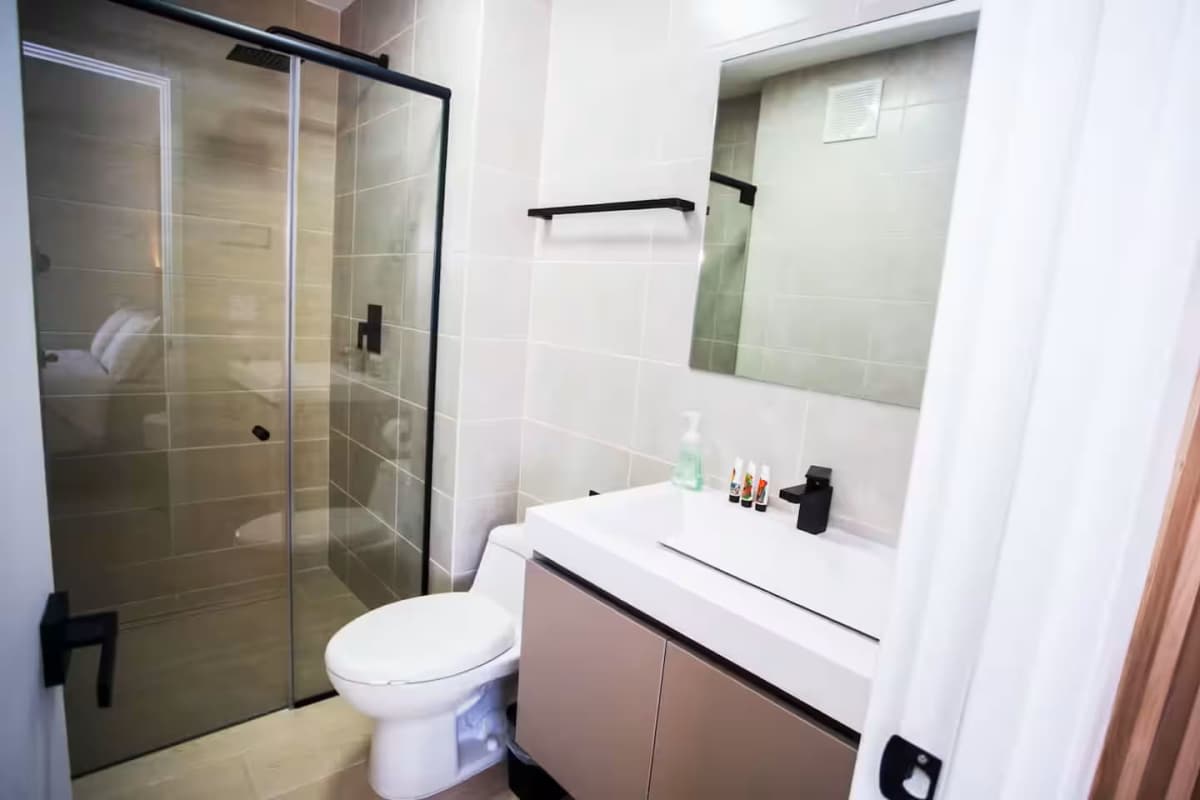 Modern bathroom with glass shower, matte black fixtures in furnished apartment PH Living 73