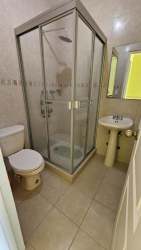 Compact bathroom with glass shower, pedestal sink, modern tile at Playa Malibú