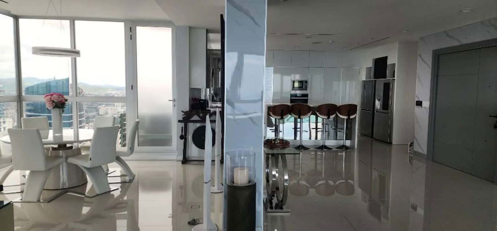 Elegant living room with floor-to-ceiling windows, marble accent wall, panoramic ocean views and a piano in Costa del Este luxury apartment