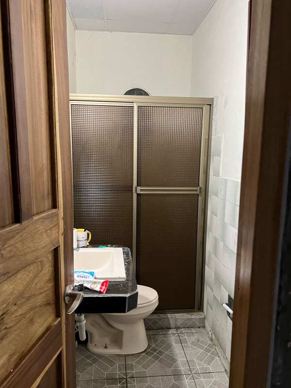 Bathroom with sliding shower enclosure, sink, and tiled walls in home for sale Panama