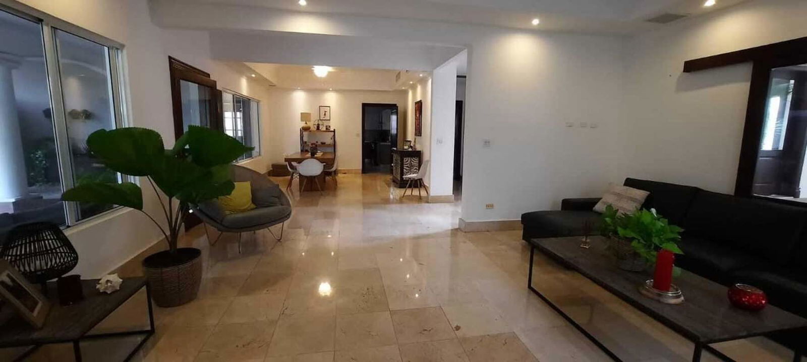 Modern living room with chandelier, wall art, black sectional sofa and tile flooring in Costa del Este luxury rental