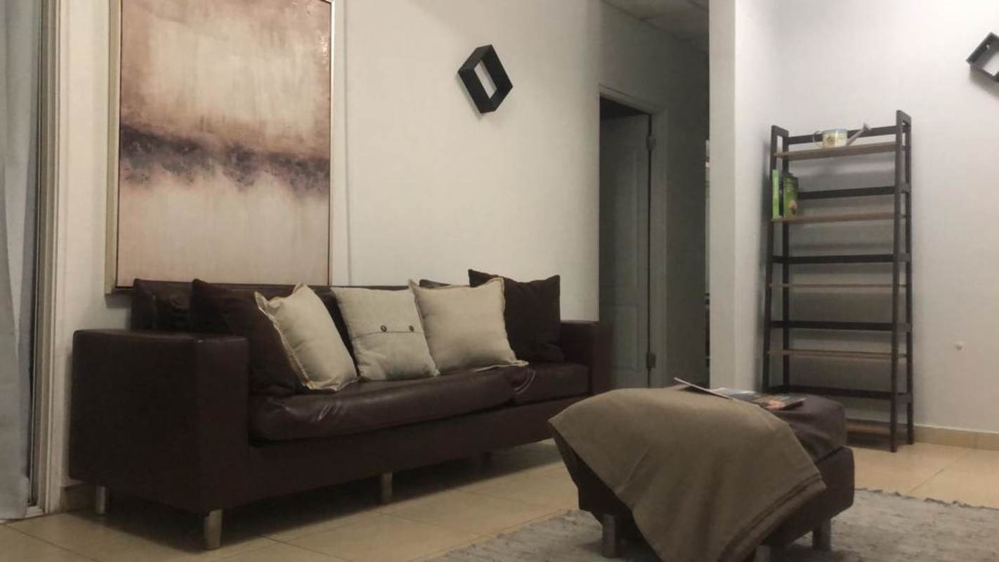 Living room with brown leather sofa, abstract artwork in shared student house Villa Cáceres Panama City