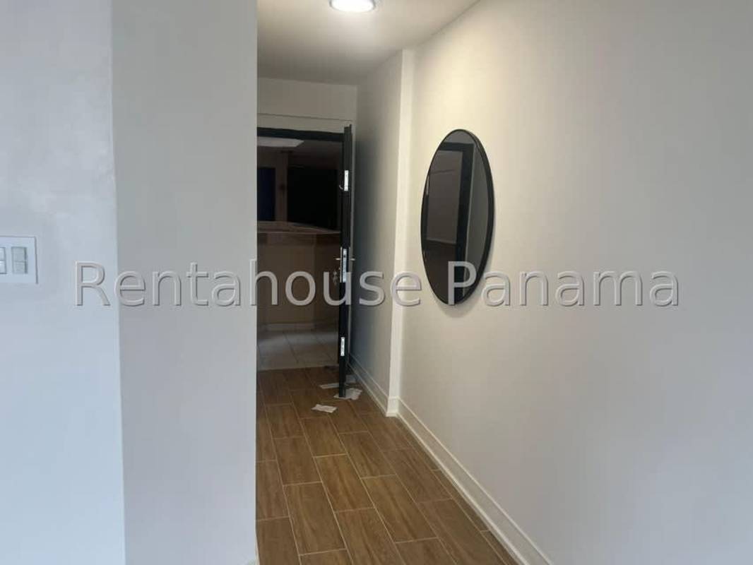 Entrance hallway with wood-look tile flooring, white walls, large mirror at PH Costa del Este Gardens Panama