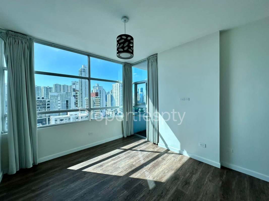 Bright modern room with large windows offering city skyline view minimalist decor and wood flooring in Panama City