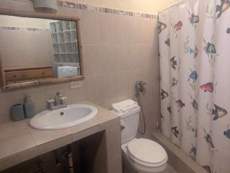 Spacious coastal bathroom with beige tiles and fish-pattern shower curtain Palenque Panama
