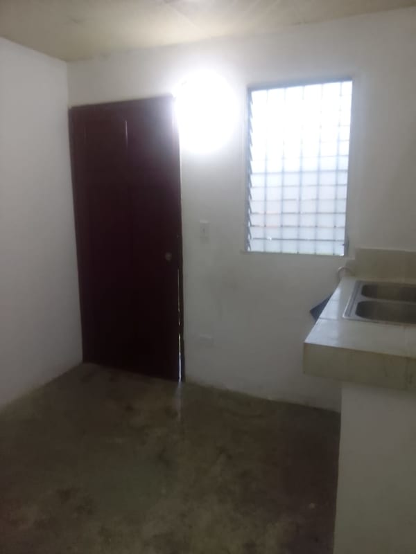 Minimalist utilitarian kitchen with concrete floor, small sink and barred glass block window in Nuevo Tocumen rental