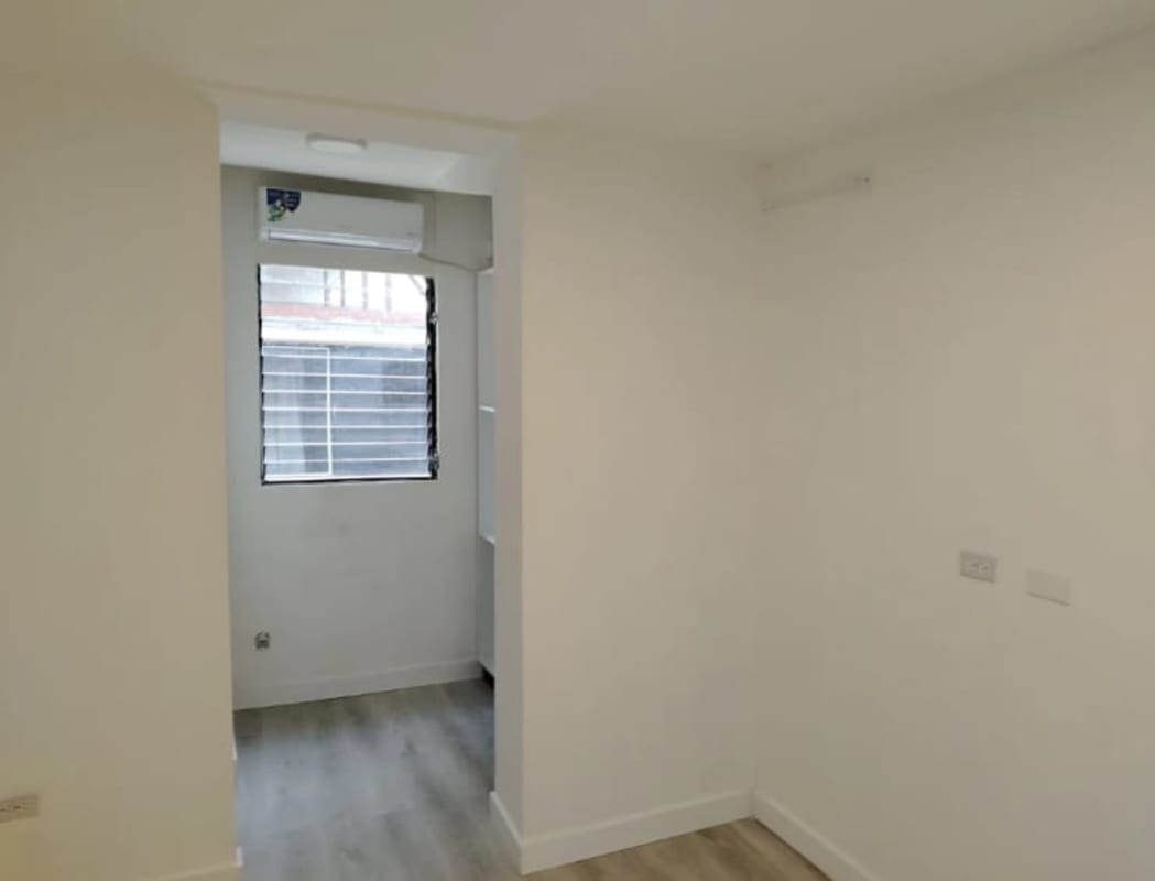 Minimalist kitchen with black countertop, white cabinets, large windows PH Plaza 77 Via Argentina Panama