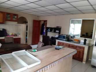 Traditional kitchen with tiled countertops, wood cabinets, large window, and dining area in Volcán Panama