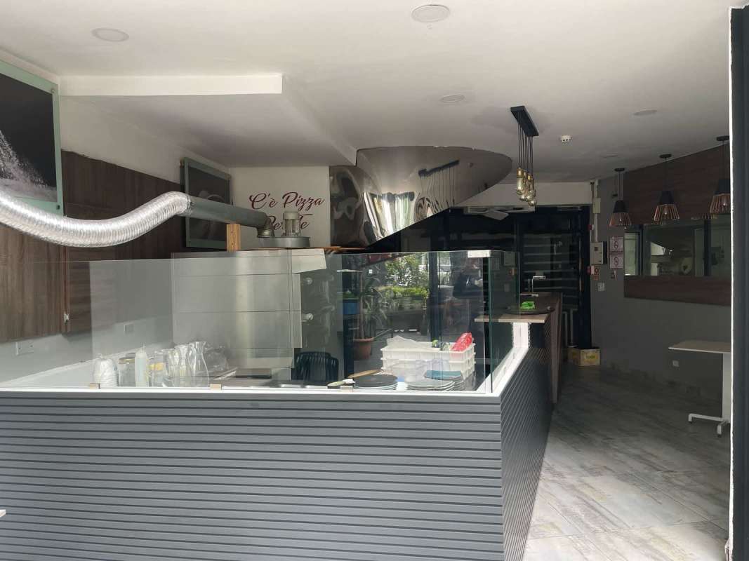 Modern restaurant interior with display counter, pizza oven, and pendant lights in Marbella Panama