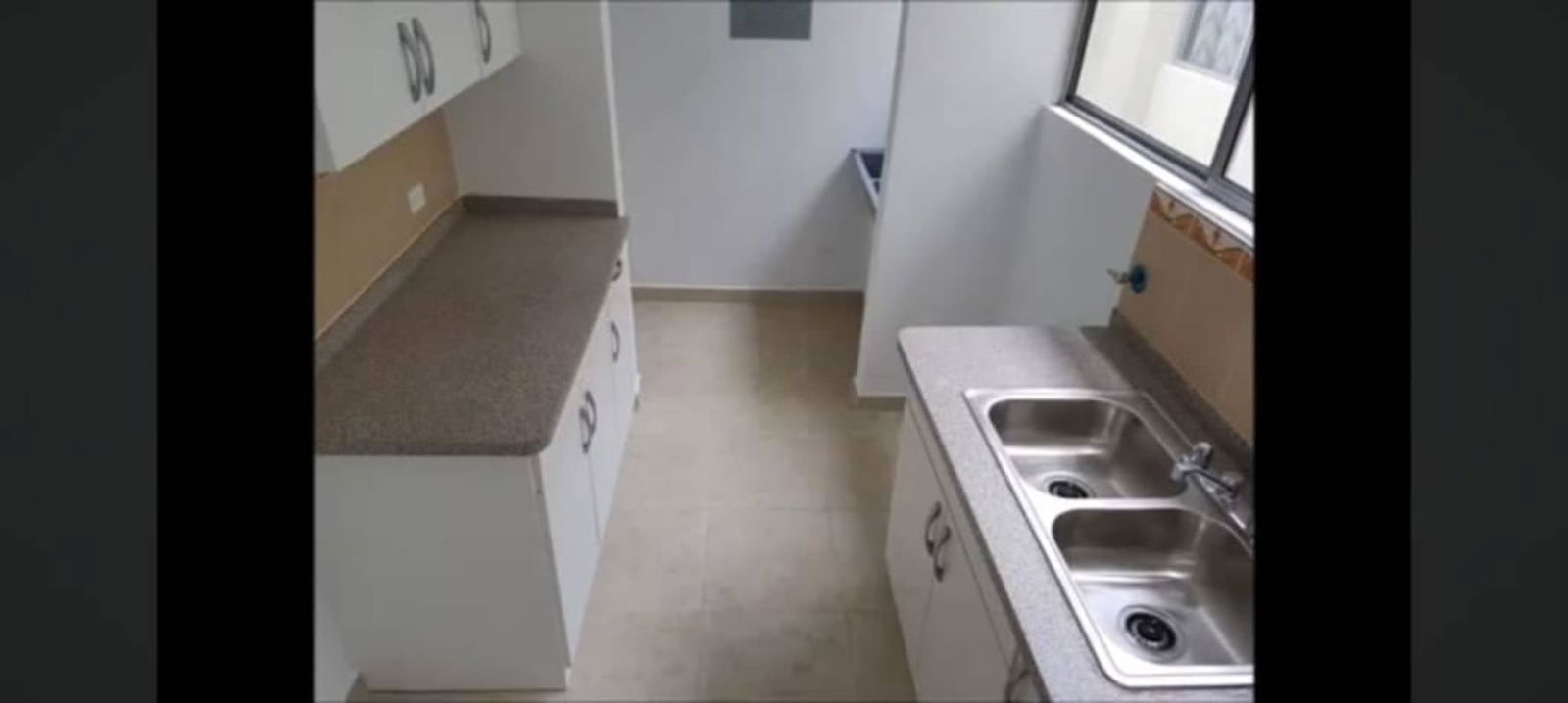 Contemporary kitchen with granite countertops, double sink, cabinets and window at PH Mystic Towers Río Abajo Panama