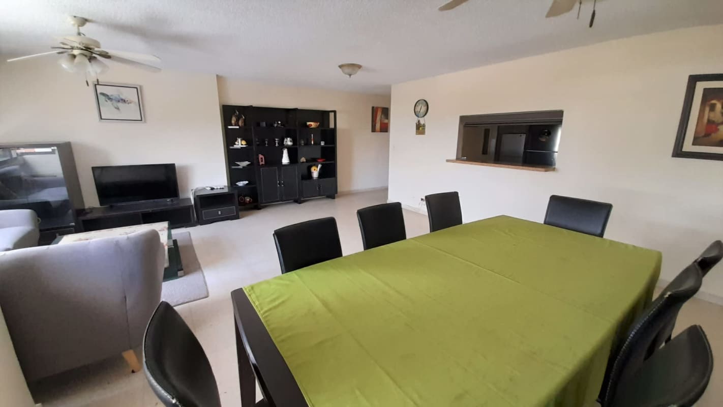 Dining area with green tablecloth, sofa, entertainment unit PH Marfil Obarrio Panama