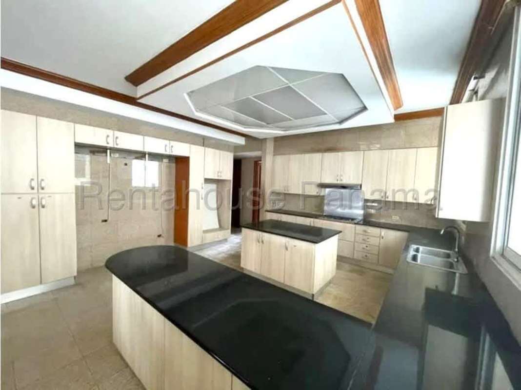 Large kitchen with granite island, wooden cabinets and ocean views in luxury Punta Paitilla Panama apartment