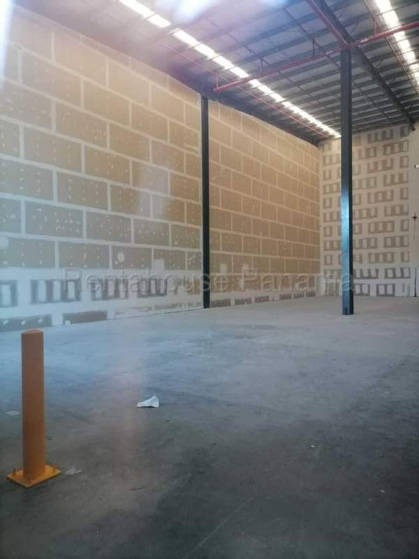 Empty industrial warehouse space with unfinished drywall, concrete floors, metal beams, overhead lighting in Panama