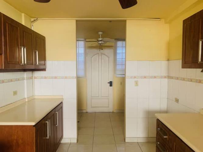 Interior staircase with white tiles, wooden handrails and bright window in Betania Panama house