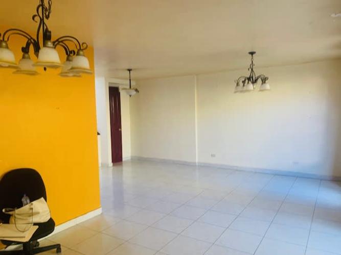 Spacious living room with yellow accent wall and chandeliers in Betania Panama City