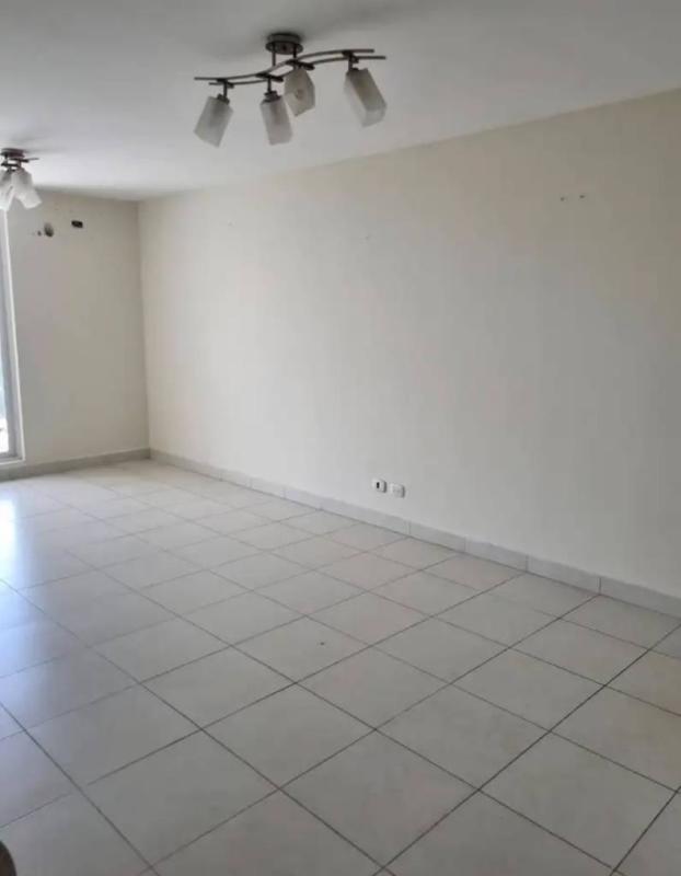 Living area with white tiled floors, large window in apartment at Torres de Cantabria Panama City