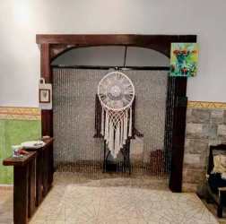 Rustic hallway with wooden arch, bead curtain, and wall art in country house in Tinajas Dolega Panama