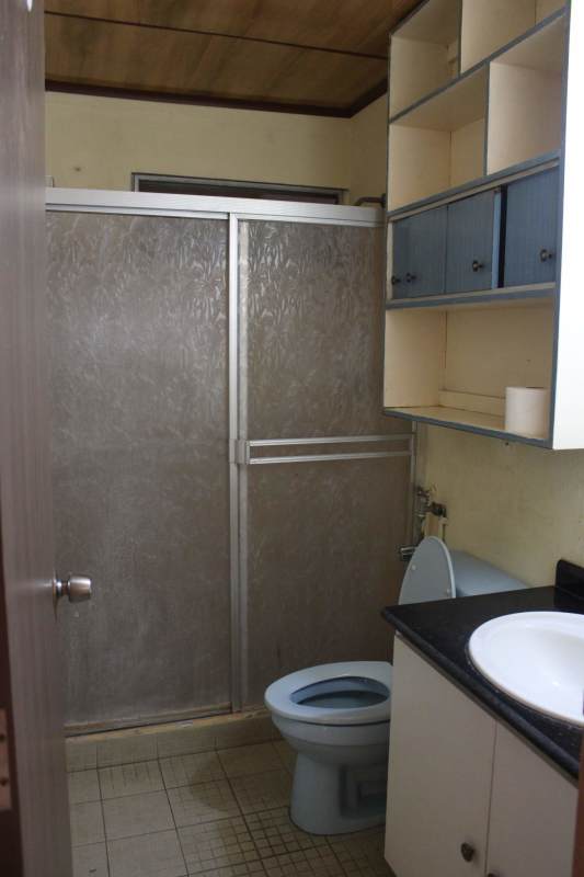 Bedroom with air conditioner, window bars, and wooden wardrobe in house Panama City