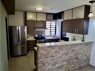 Modern open kitchen featuring stone breakfast bar, cabinetry, stainless steel appliances in Palmia, Panama Pacifico